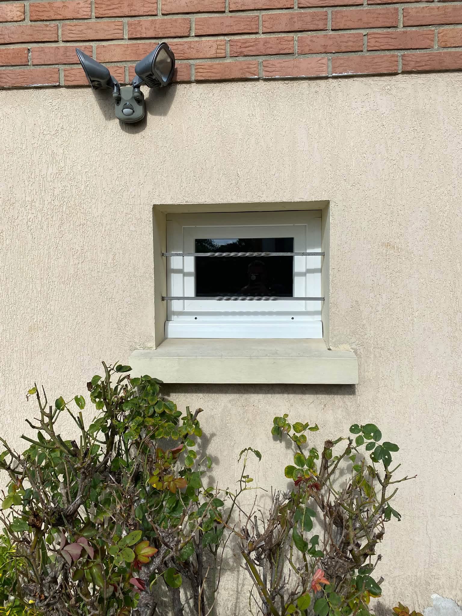 Petite fenêtre PVC blanche avec grille de sécurité