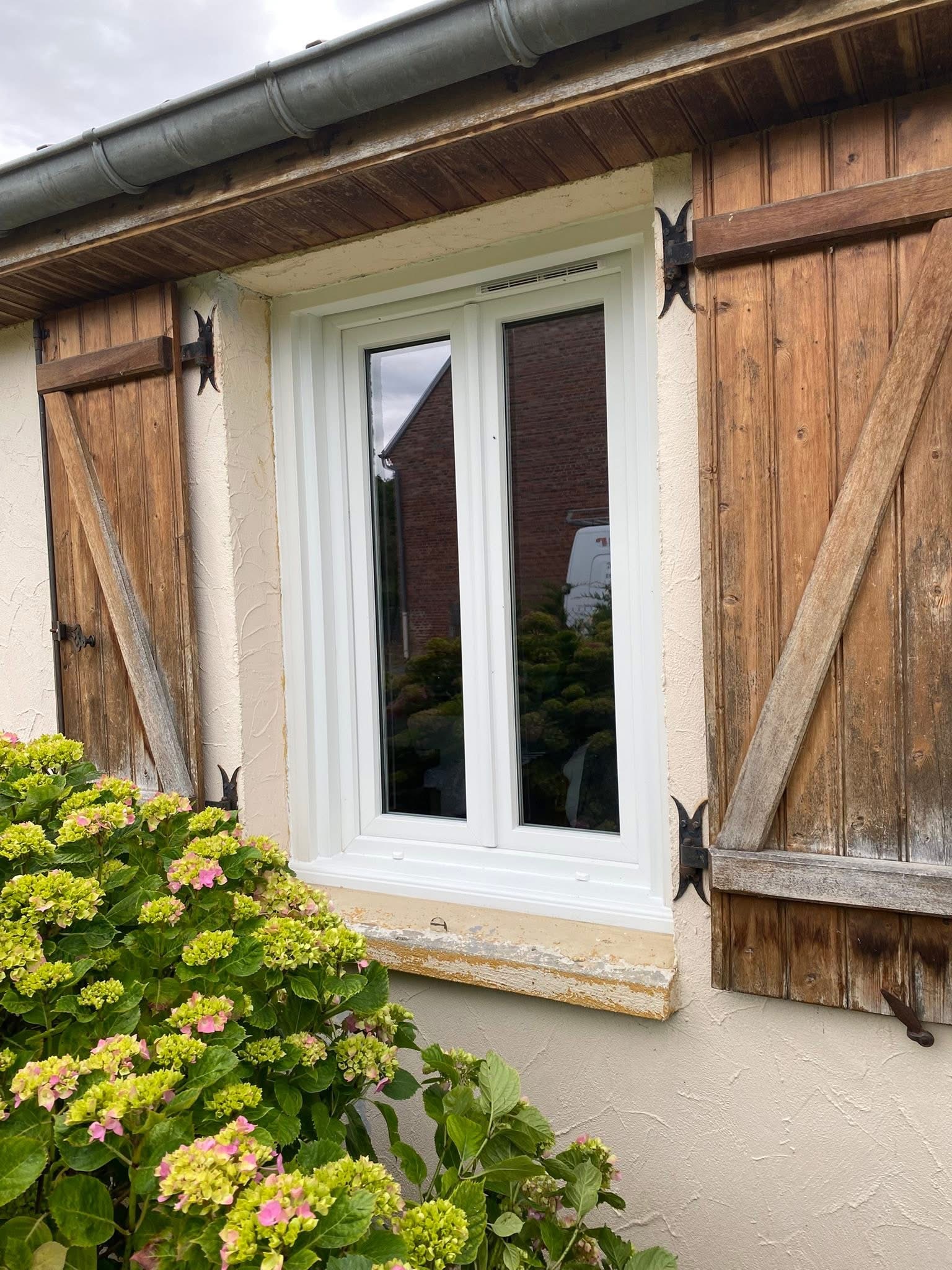 Fenêtre PVC blanche à deux vantaux avec volets bois